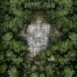 Discover the ancient Chacchoben pyramid nestled in lush greenery from a high aerial perspective.